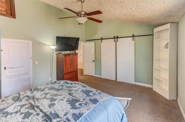 bedroom with lofted ceiling, ceiling fan, carpet, a textured ceiling, and a barn door