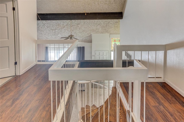 stairway with beamed ceiling, wood-type flooring, a towering ceiling, and ceiling fan