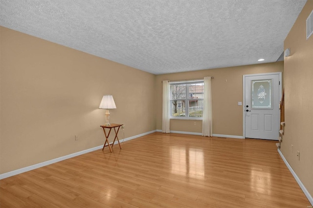 entrance foyer with a textured ceiling and light wood-type flooring