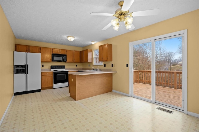 kitchen featuring ceiling fan, a textured ceiling, white appliances, and kitchen peninsula