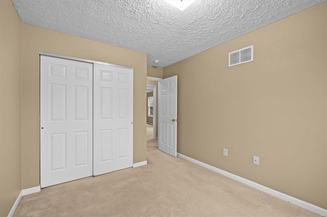 unfurnished bedroom featuring light colored carpet, a closet, and a textured ceiling