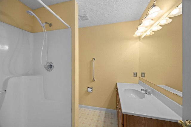 bathroom with walk in shower, vanity, and a textured ceiling