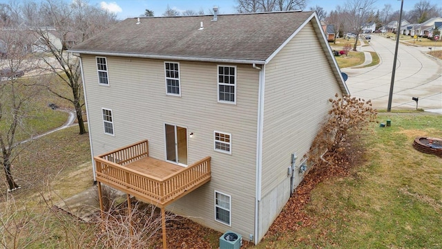 rear view of property featuring central AC unit, a lawn, and a wooden deck