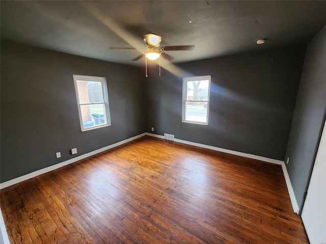 empty room featuring ceiling fan, dark hardwood / wood-style flooring, and a wealth of natural light