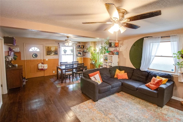 living room with dark wood-type flooring, ceiling fan, plenty of natural light, and a textured ceiling