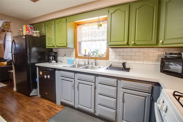 kitchen with sink, tasteful backsplash, black appliances, green cabinetry, and dark hardwood / wood-style flooring