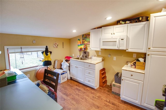 kitchen with white cabinetry, sink, and light hardwood / wood-style floors