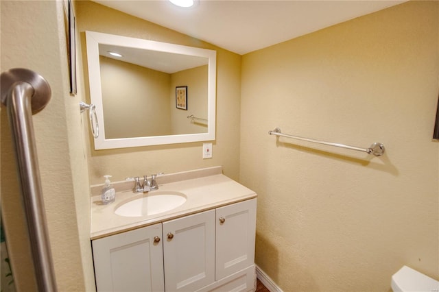 bathroom with vanity, toilet, and vaulted ceiling