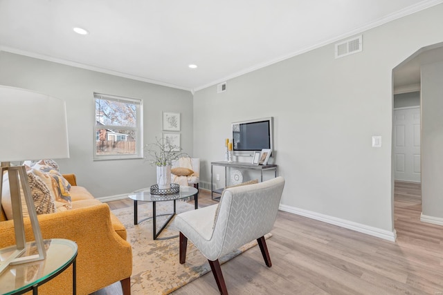 sitting room featuring arched walkways, crown molding, baseboards, and light wood-style floors