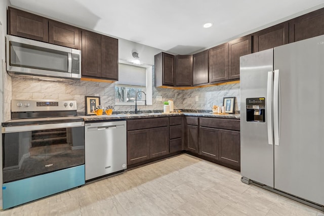 kitchen with appliances with stainless steel finishes, a sink, decorative backsplash, and dark brown cabinetry