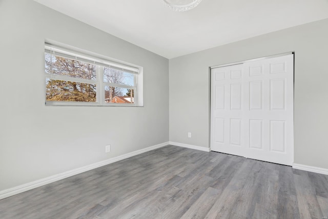 unfurnished bedroom featuring a closet, baseboards, and wood finished floors