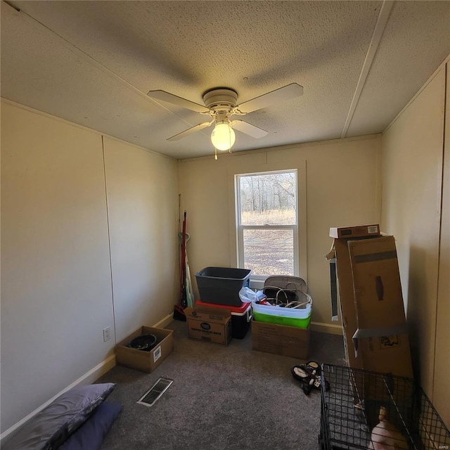 misc room with ceiling fan, a textured ceiling, and dark colored carpet