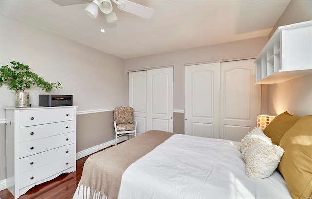 bedroom featuring two closets, dark hardwood / wood-style floors, and ceiling fan