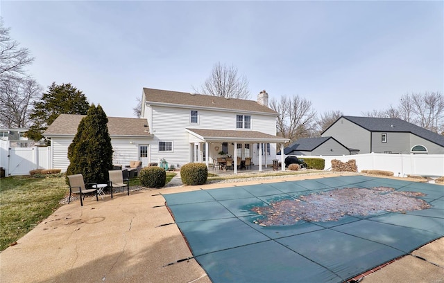 back of property featuring a covered pool and a patio