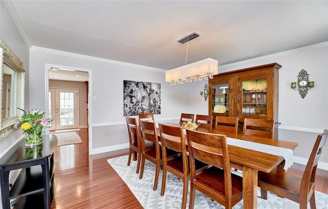 dining area with crown molding and hardwood / wood-style floors