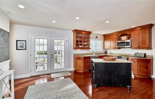 kitchen featuring sink, light stone countertops, a kitchen island, dark hardwood / wood-style flooring, and french doors