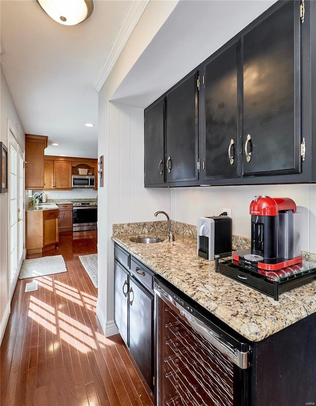 kitchen featuring appliances with stainless steel finishes, sink, dark wood-type flooring, and light stone counters