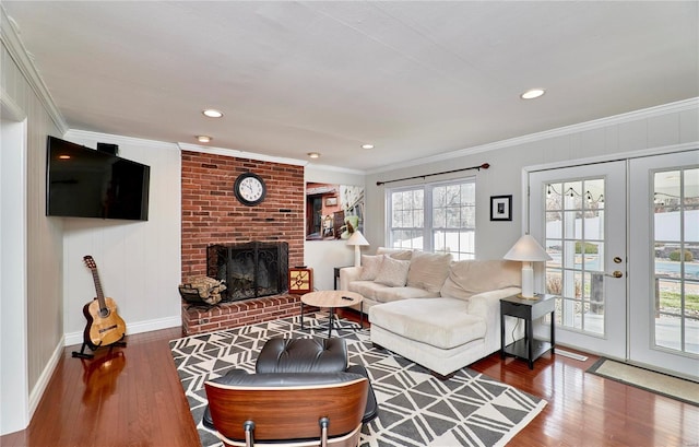 living room featuring hardwood / wood-style floors, ornamental molding, french doors, and a brick fireplace