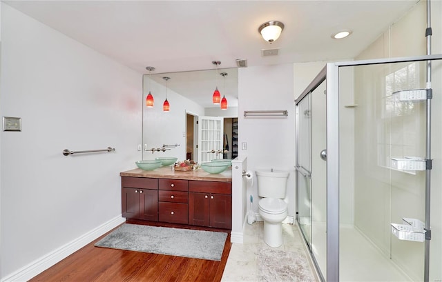 bathroom featuring vanity, wood-type flooring, a shower with shower door, and toilet