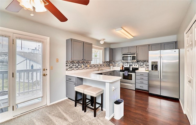 kitchen featuring a kitchen bar, sink, kitchen peninsula, stainless steel appliances, and backsplash