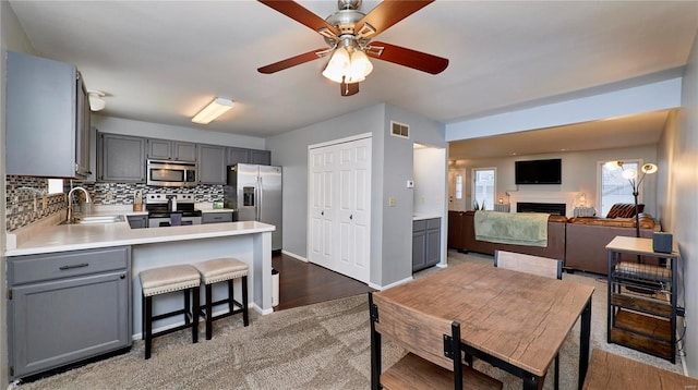 kitchen with gray cabinetry, sink, tasteful backsplash, and appliances with stainless steel finishes