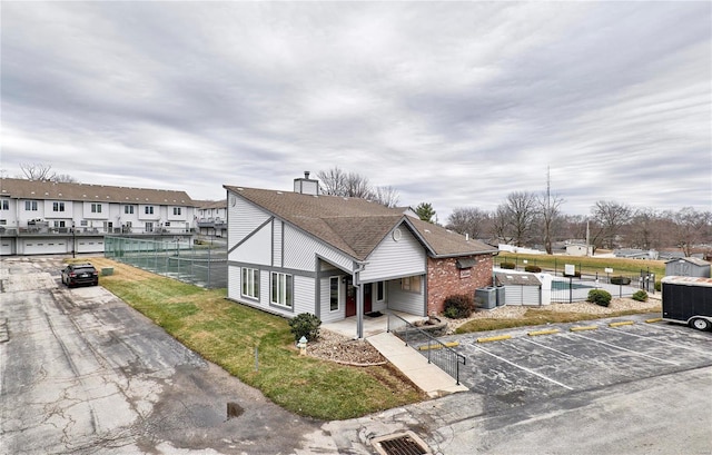 view of front of home with central AC unit and a front lawn