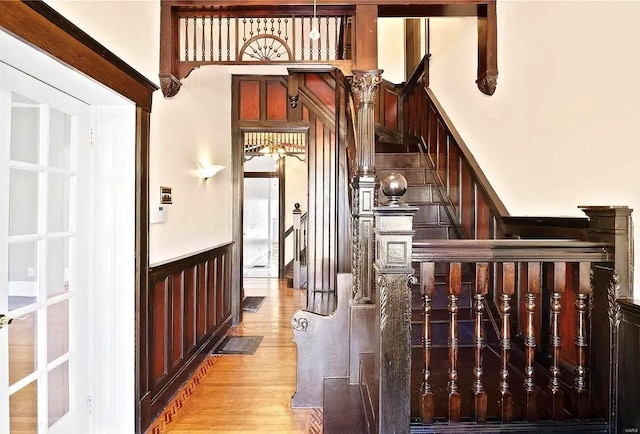 staircase with a wainscoted wall and wood finished floors