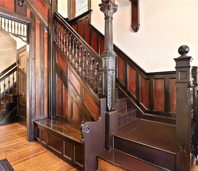 stairway with a decorative wall and wood finished floors