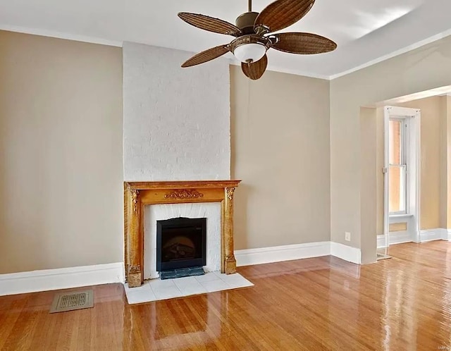 unfurnished living room featuring ornamental molding, a high end fireplace, light wood-style floors, and baseboards