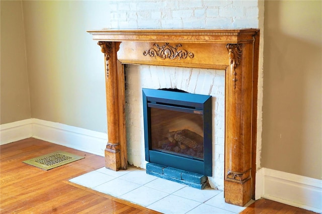 details with a fireplace with flush hearth, visible vents, and wood finished floors