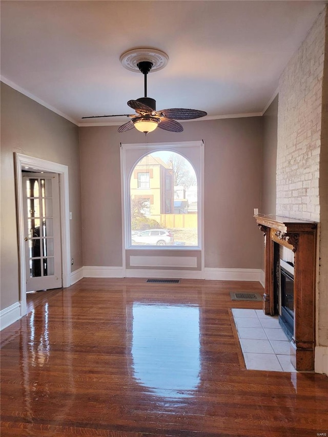 unfurnished living room with ornamental molding, light wood-type flooring, visible vents, and a fireplace