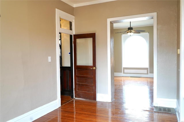 interior space with ceiling fan, ornamental molding, wood finished floors, and baseboards