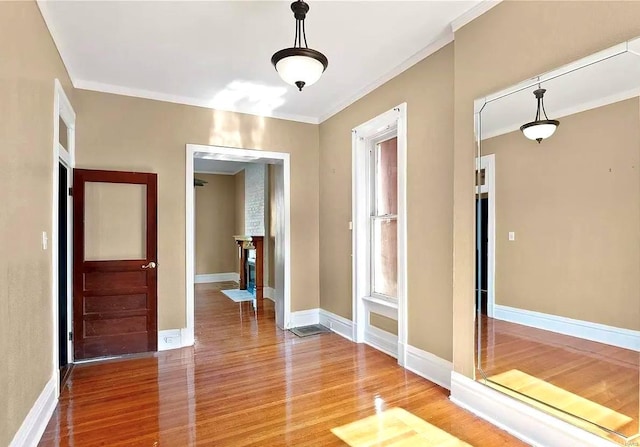 empty room with crown molding, baseboards, and wood finished floors