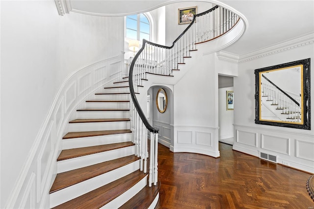 foyer entrance featuring crown molding, parquet flooring, and a towering ceiling