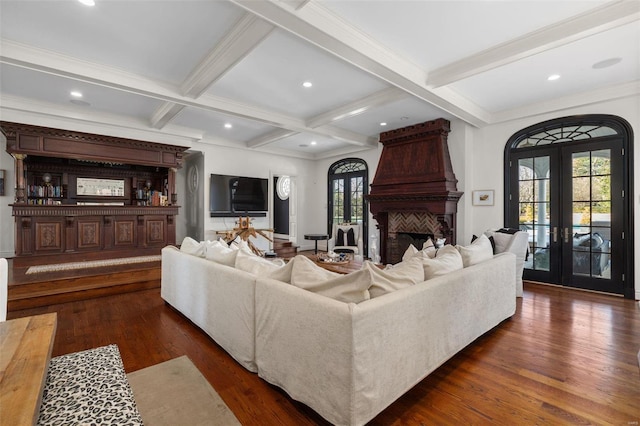 living room with beamed ceiling, a large fireplace, coffered ceiling, dark wood-type flooring, and french doors