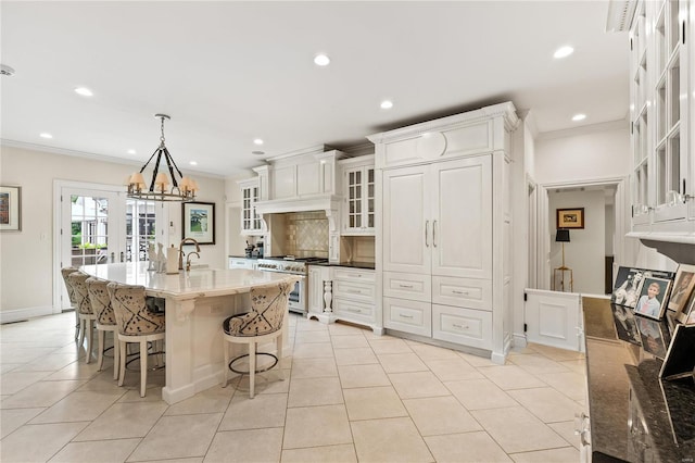 kitchen featuring hanging light fixtures, stainless steel range, dark stone counters, and white cabinets