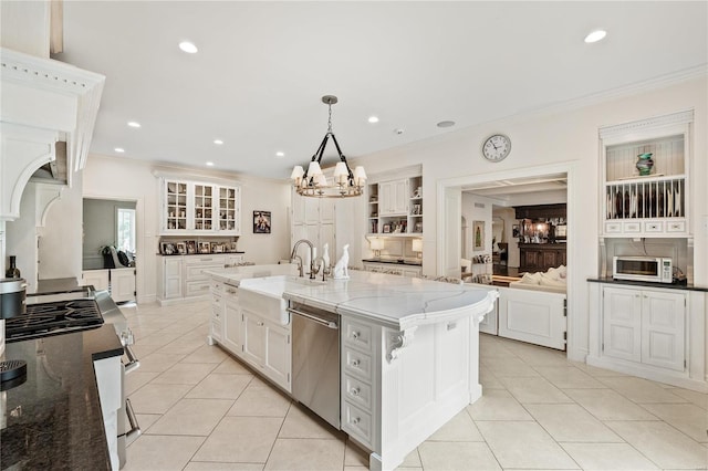 kitchen with a kitchen bar, decorative light fixtures, a center island with sink, stainless steel dishwasher, and white cabinets