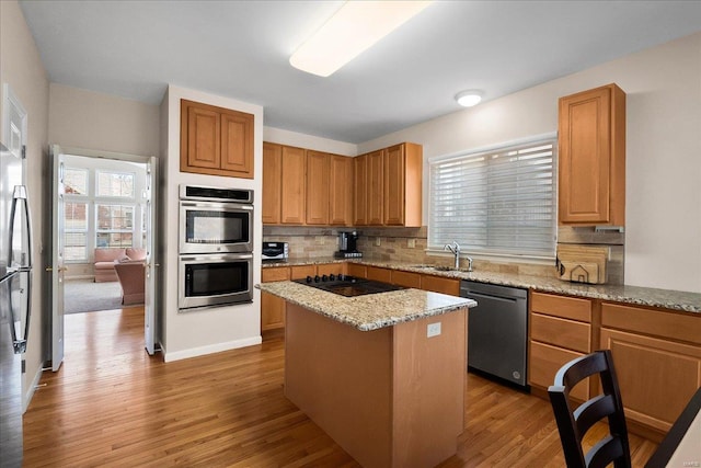 kitchen featuring stainless steel appliances, a sink, backsplash, and wood finished floors