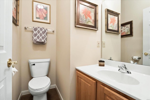 bathroom with baseboards, vanity, and toilet