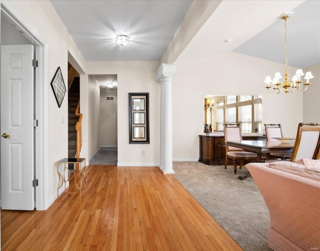 entryway with decorative columns, stairway, vaulted ceiling, light wood-style floors, and a chandelier