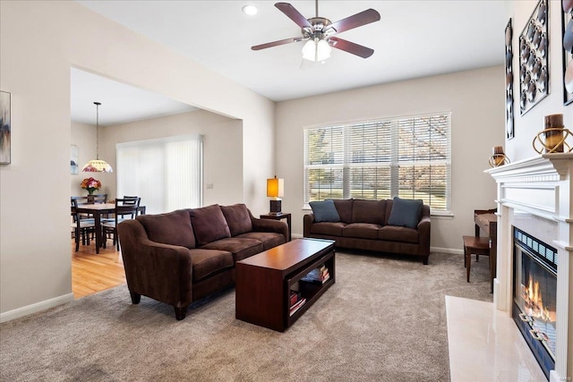 carpeted living room with a ceiling fan, a fireplace, and baseboards