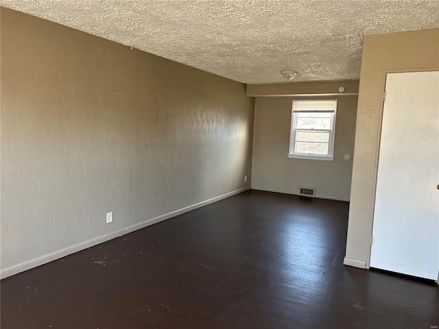 unfurnished room with dark hardwood / wood-style flooring and a textured ceiling