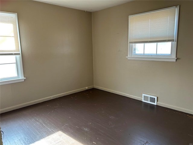 empty room featuring plenty of natural light and dark hardwood / wood-style flooring