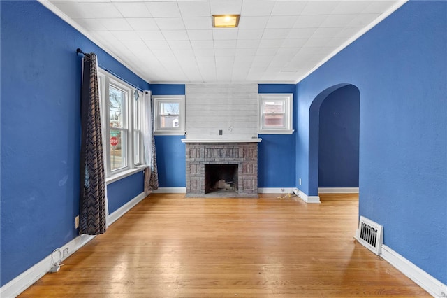 unfurnished living room with a brick fireplace, light hardwood / wood-style flooring, and ornamental molding