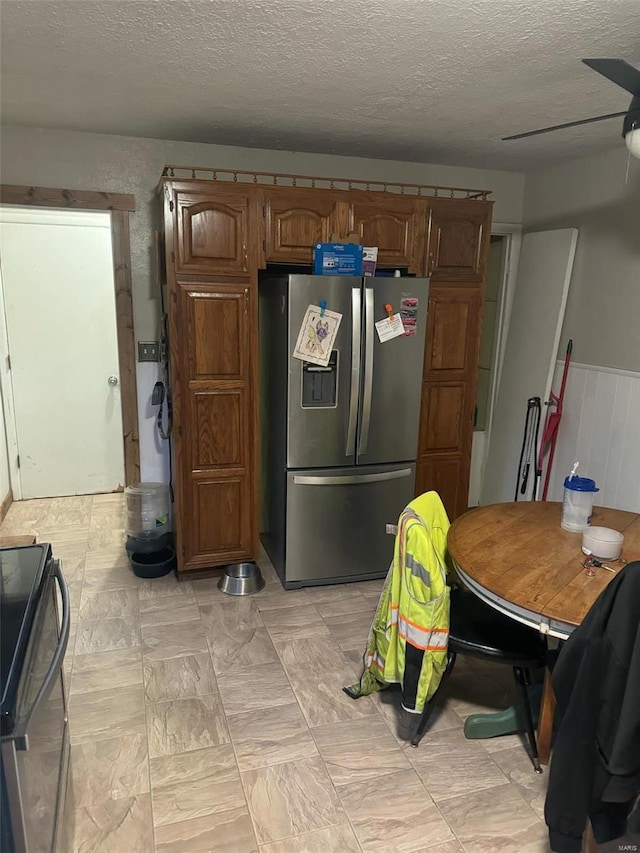 kitchen with stainless steel fridge with ice dispenser, a textured ceiling, range with electric cooktop, and ceiling fan