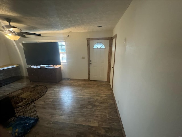 foyer featuring ceiling fan, dark wood-type flooring, and a textured ceiling