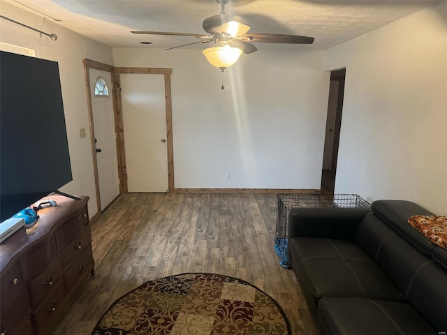 living room featuring ceiling fan, dark hardwood / wood-style floors, and a textured ceiling