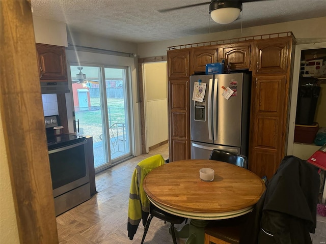 kitchen featuring stainless steel appliances, ceiling fan, and a textured ceiling