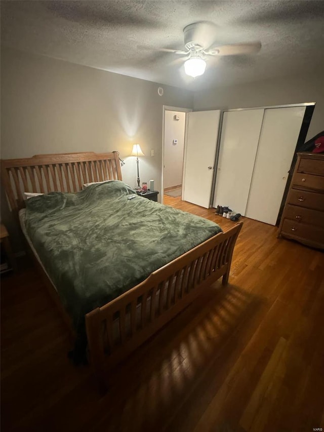 bedroom with ceiling fan, dark hardwood / wood-style flooring, and a textured ceiling