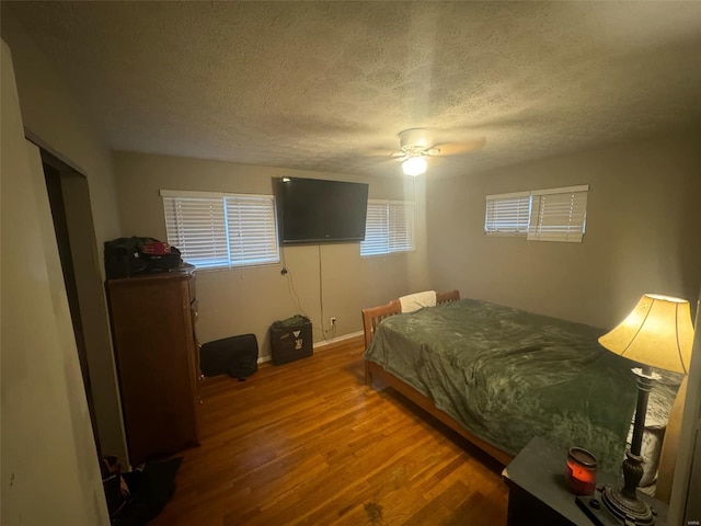 bedroom with ceiling fan, hardwood / wood-style floors, and a textured ceiling